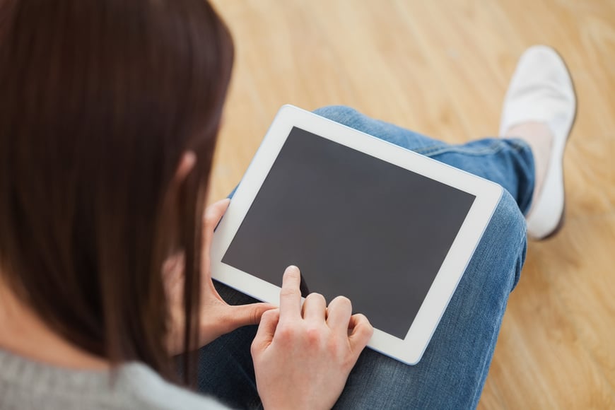 Brunette using a tablet pc sitting on the floor in a living room