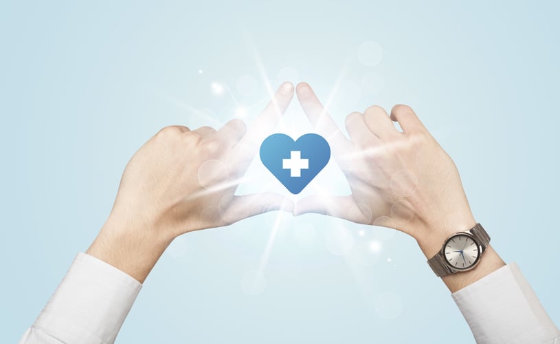 Hands coming together and a blue heart radiating from the middle with a white cross inside the heart.